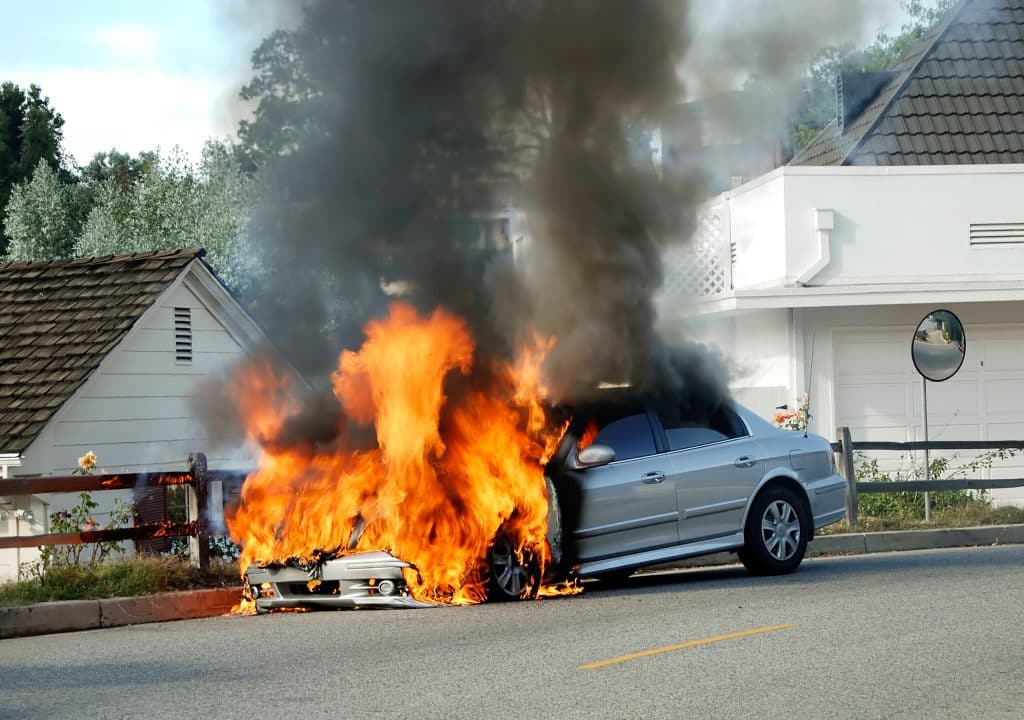 Car on fire on the side of the road.