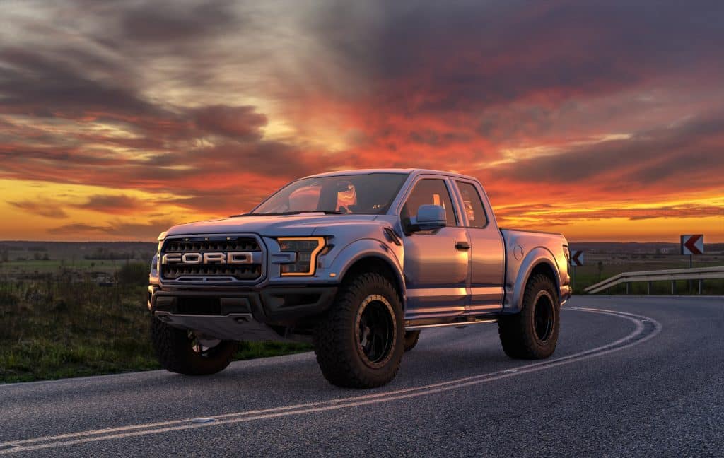 Silver 2020 Ford F-150 parked on a winding road at sunset.