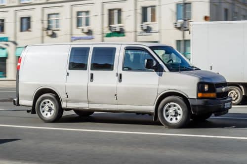 Grey Chevrolet Express driving on the street. 