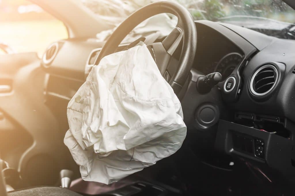 Deflated airbag in a car with a black interior.