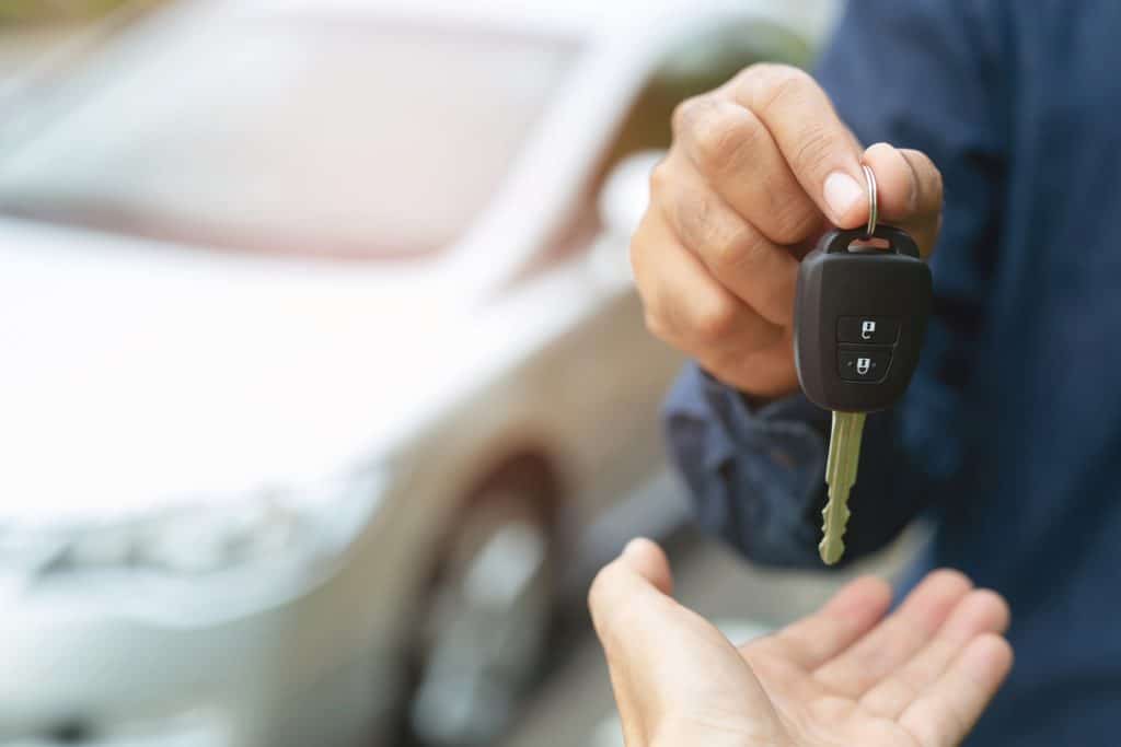 Man in blue shirt placing a car key into a woman's hand.