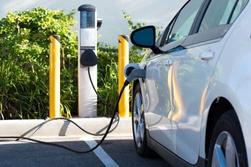 White electric car charging at a charging station in a parking lot. 