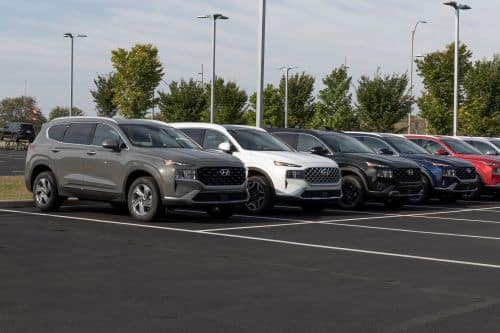 A line of grey, white, black, navy blue, and red Hyundai Santa Fe's at a dealership.