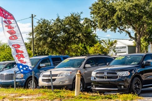Line of blue, silver, and black cars at a used car dealership.